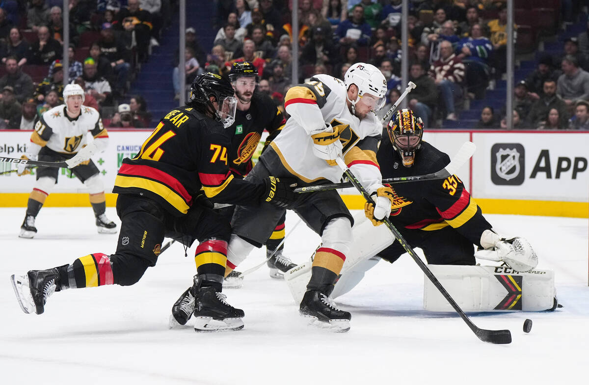 Vancouver Canucks' Ethan Bear (74) checks Vegas Golden Knights' Ivan Barbashev (49) in front of ...