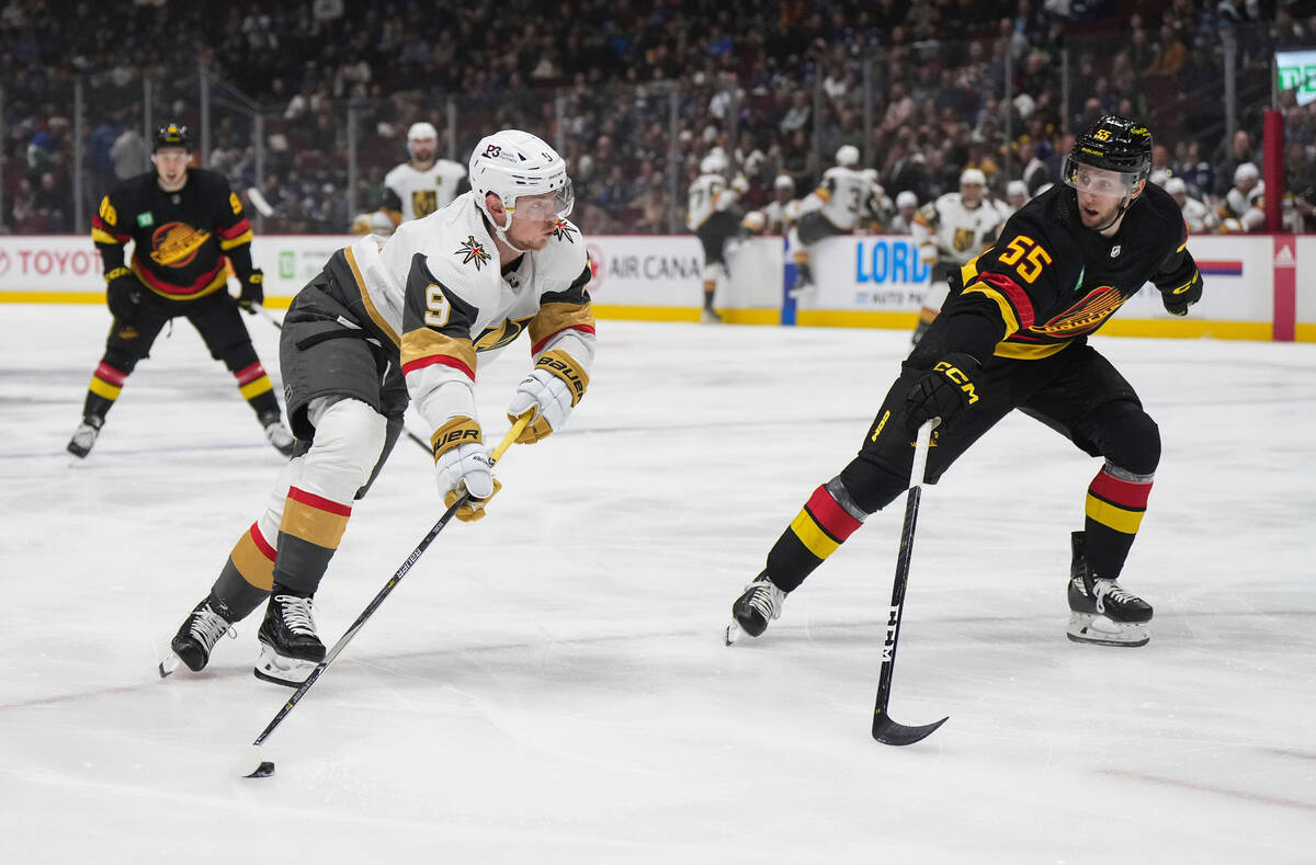 Vegas Golden Knights' Jack Eichel, left, shoots as Vancouver Canucks' Guillaume Brisebois defen ...