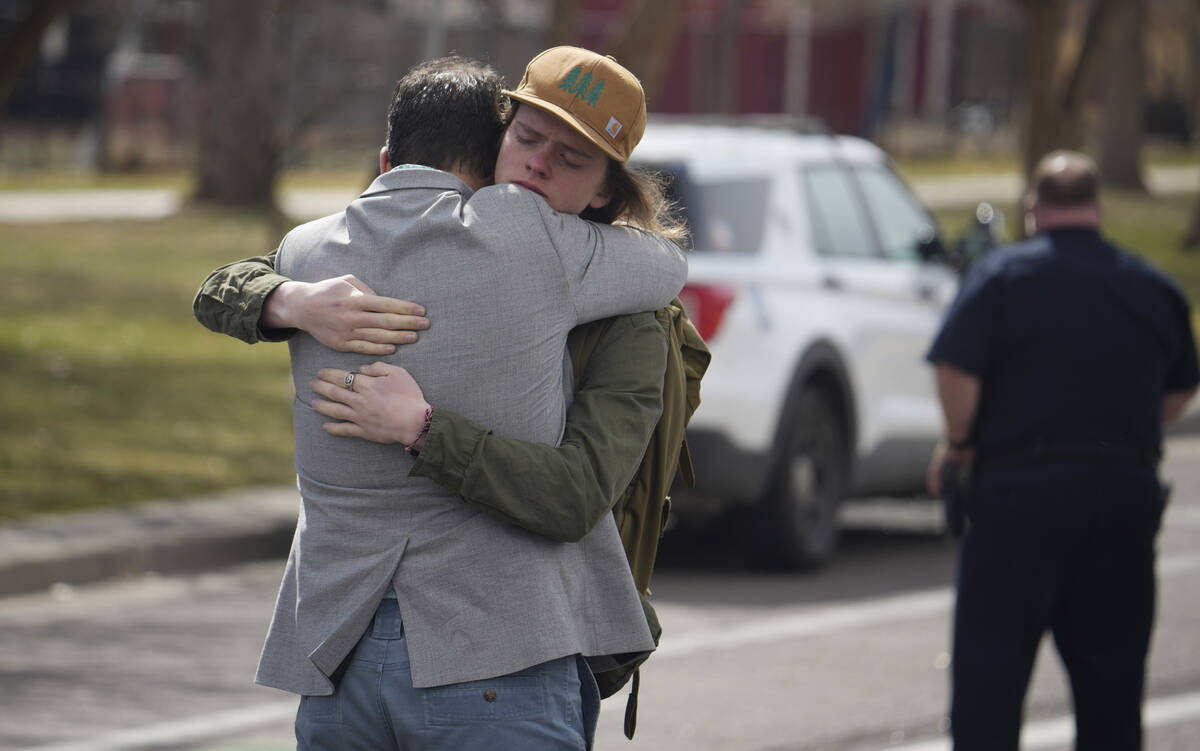 A student, right, hugs a man after a school shooting at East High School Wednesday, March 22, 2 ...