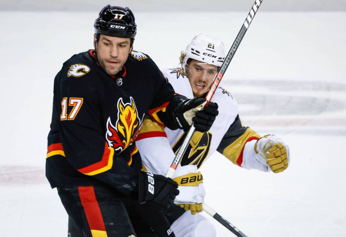 Vegas Golden Knights forward Brett Howden, right, is checked by Calgary Flames forward Milan Lu ...