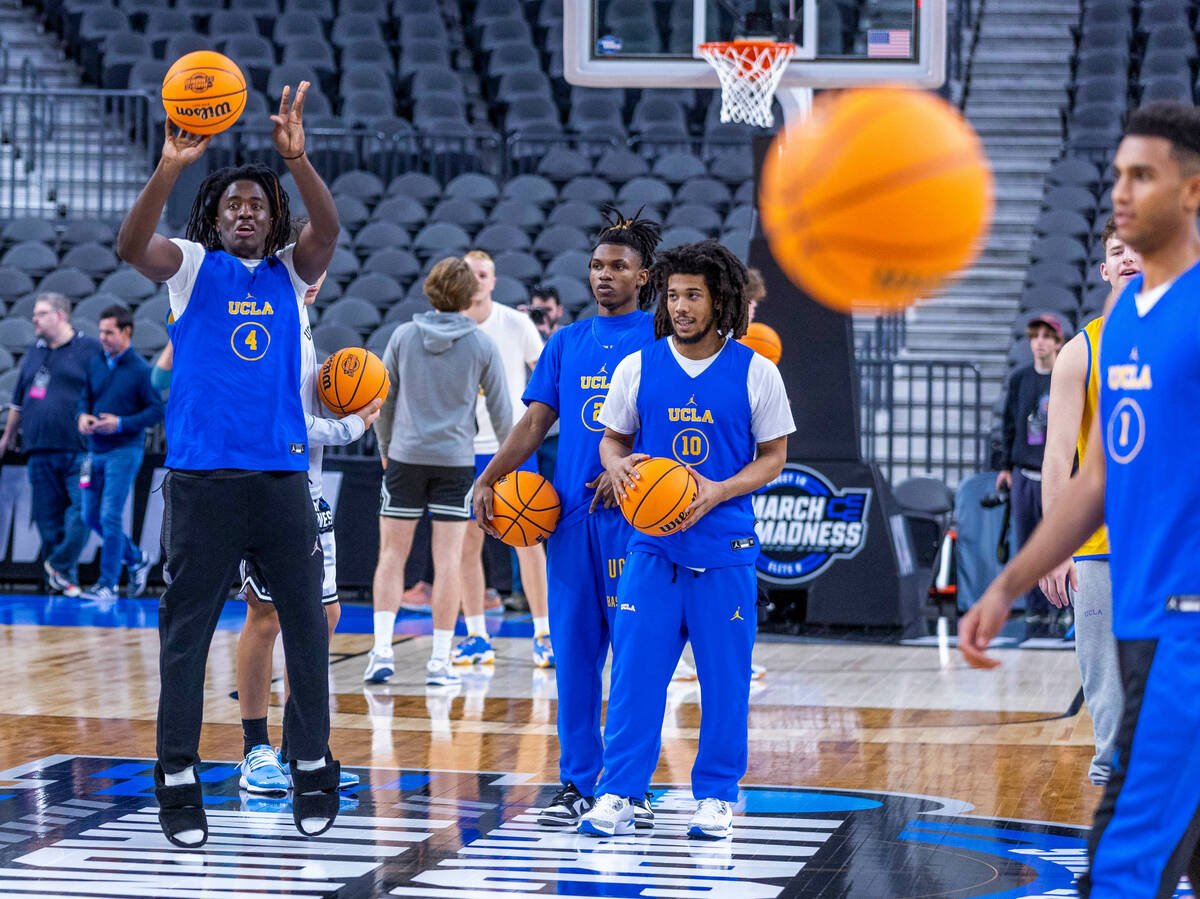 UCLA guard Will McClendon, left, releases a half-court shot as players gather on the court dur ...