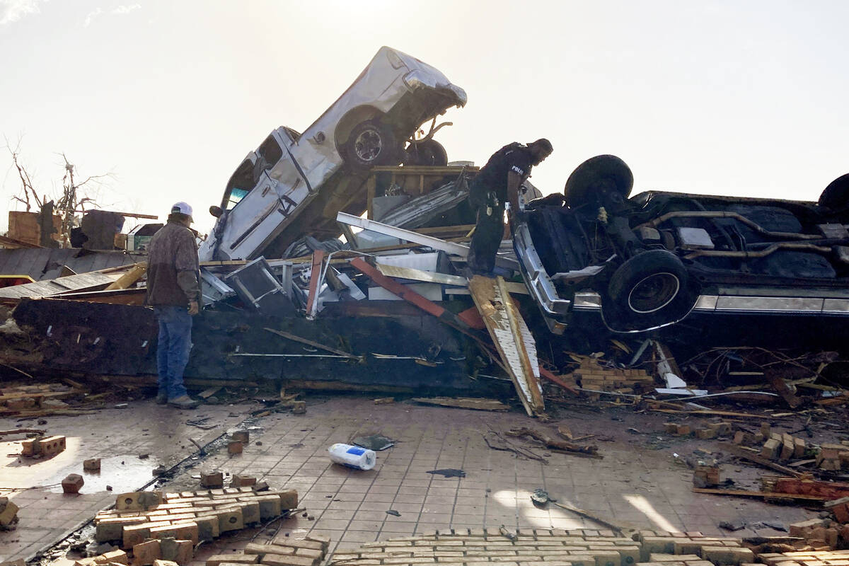 Law-enforcement officers climb through debris on a diner looking for survivors early Saturday, ...