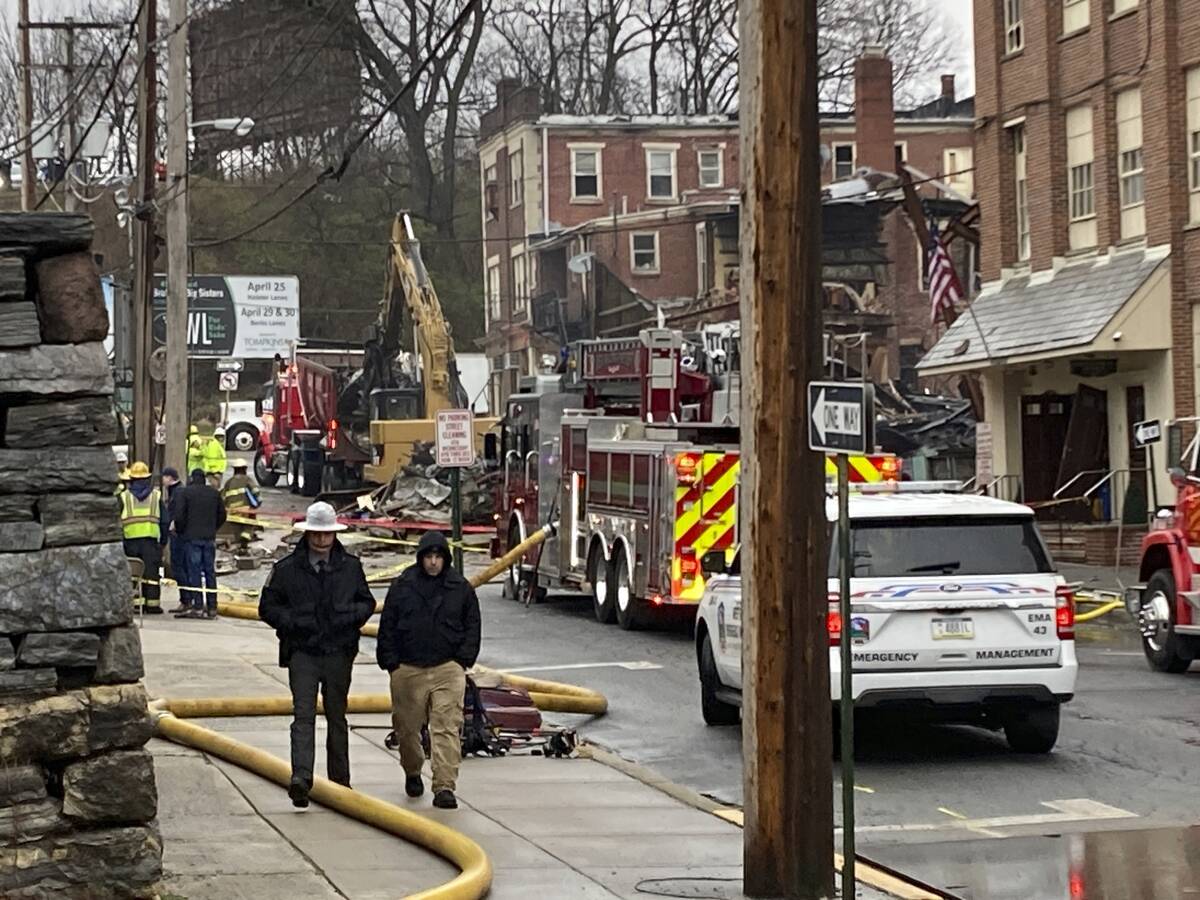 Emergency personnel and heavy equipment work at the site of a deadly explosion at a chocolate f ...