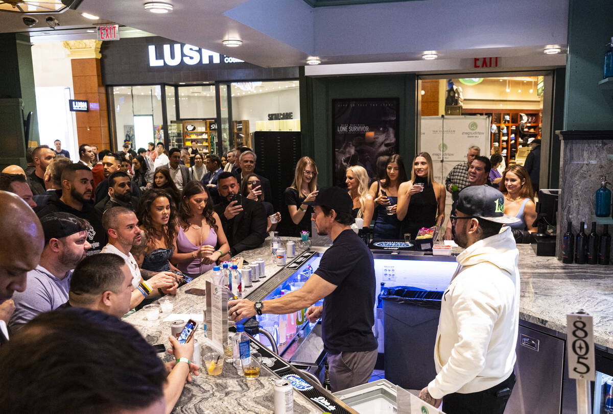 Mark Wahlberg, right, pours drinks at the bar during the opening celebration of a new Wahlburge ...