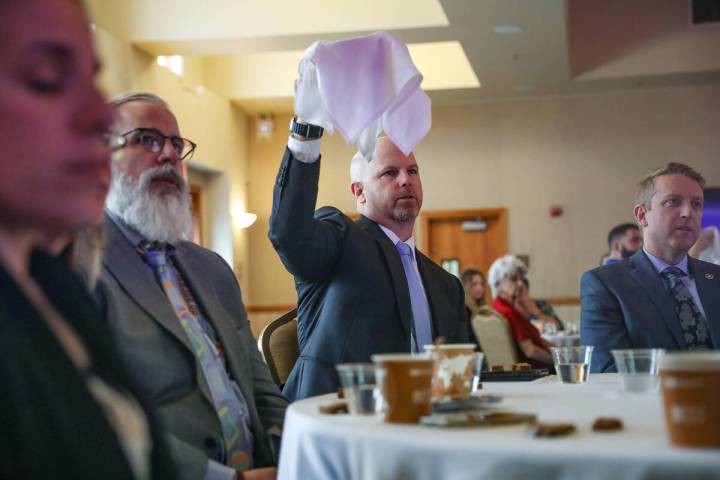 Aaron Woodill holds up a basket of matzah bread as guests recite words about the significance o ...