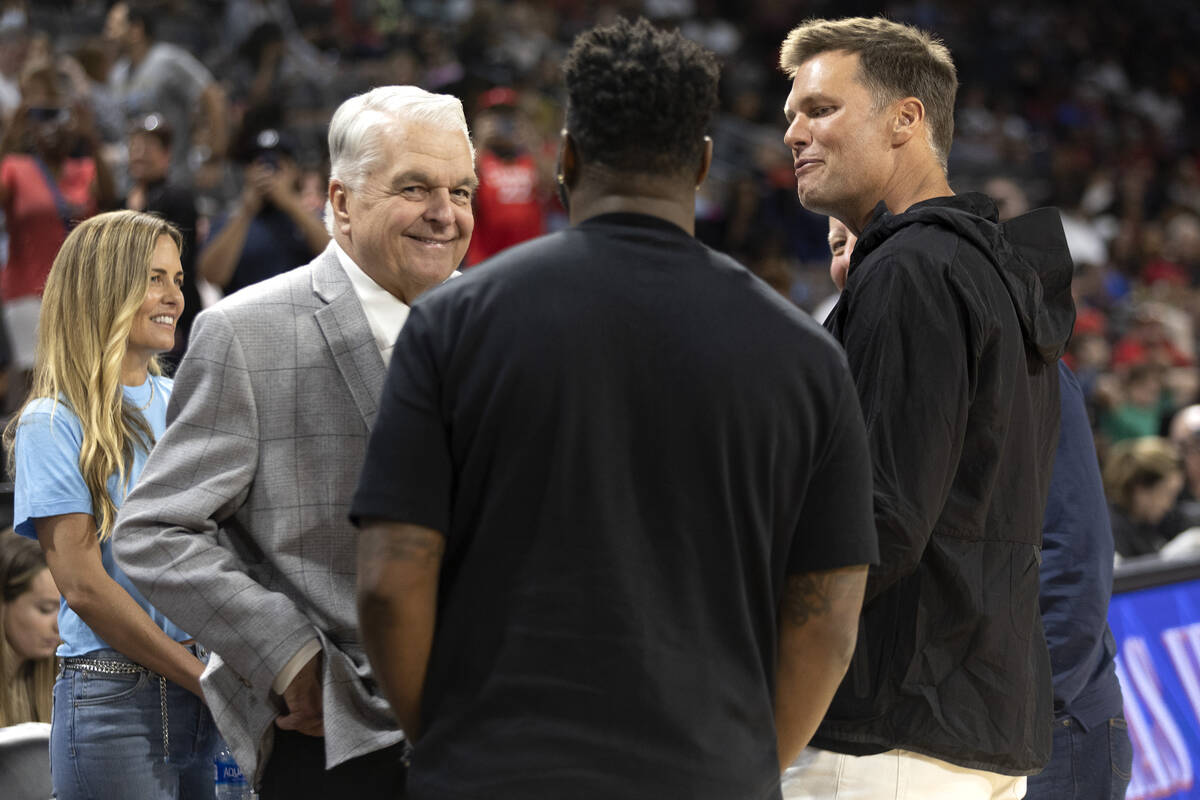 Gov. Steve Sisolak and football quarterback Tom Brady converse with a group during halftime of ...