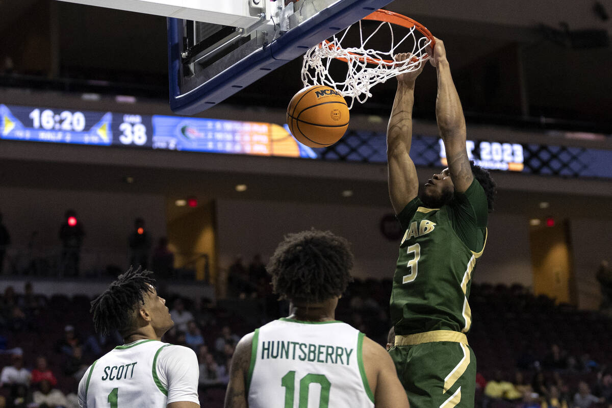 UAB Blazers guard Tavin Lovan (3) dunks while North Texas Mean Green guard Aaron Scott (1) and ...