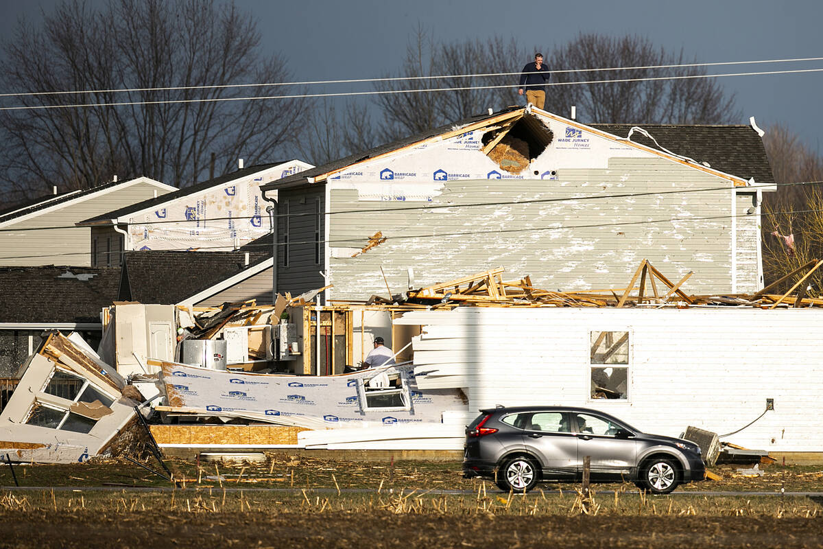 A person walks on the roof of a building damaged in a storm after a tornado warning in Johnson ...