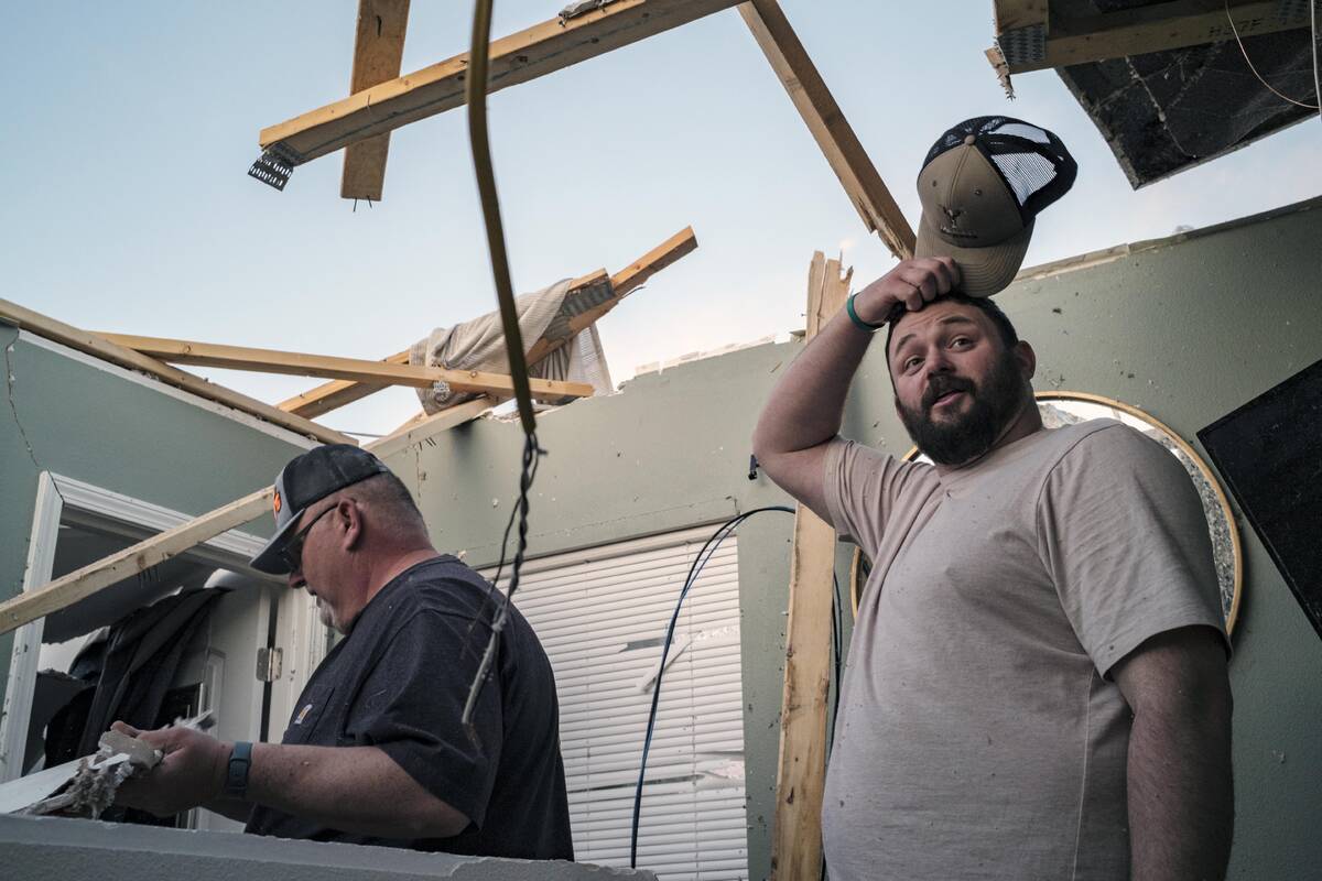 Jacob Dilks, right, looks over storm damage to his home in Hills, Iowa on Friday, March 31, 202 ...