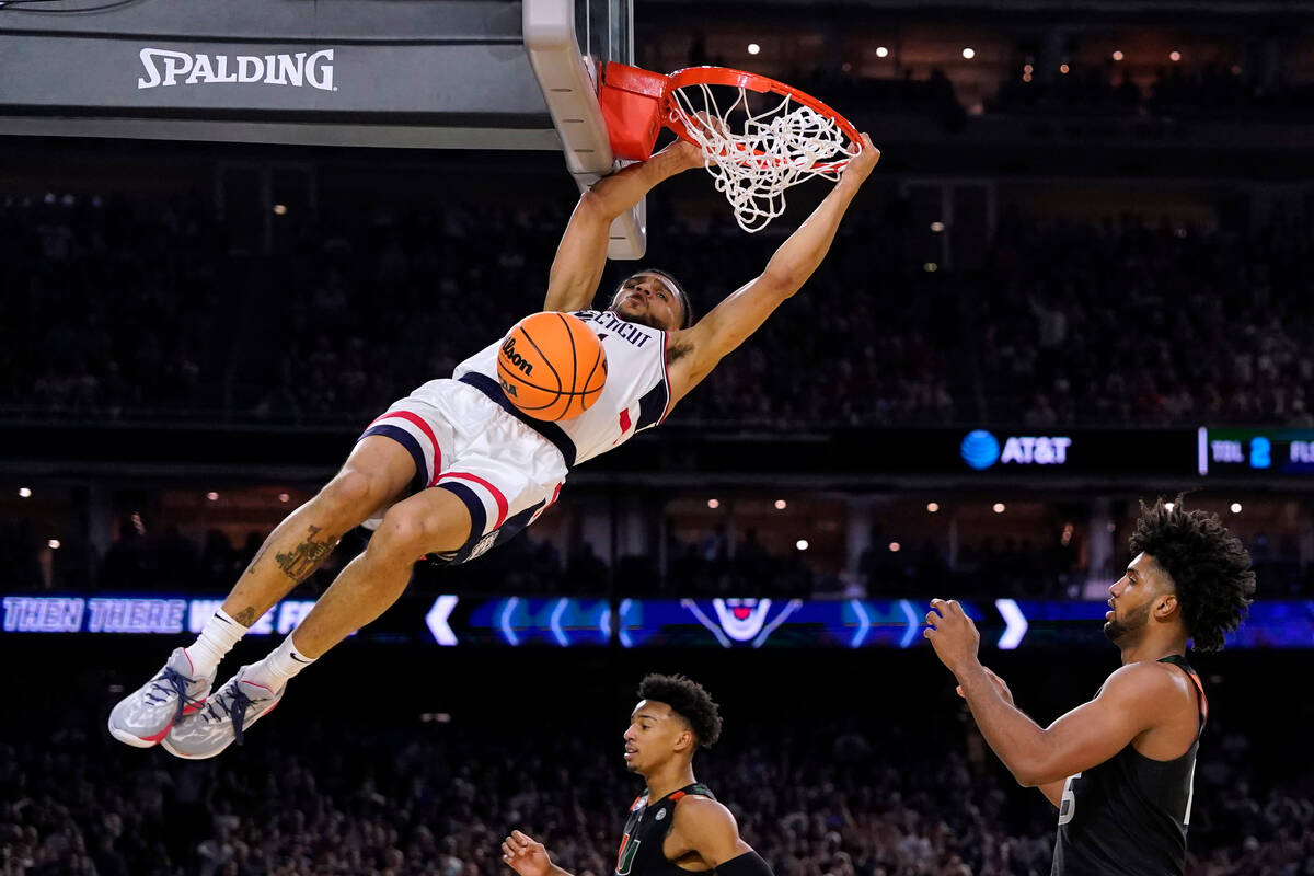 Connecticut guard Andre Jackson Jr. dunks the ball over Miami forward Norchad Omier, right, dur ...