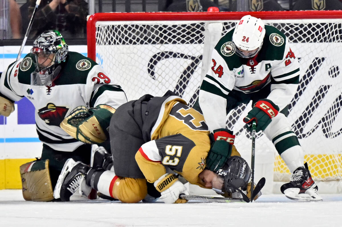 Vegas Golden Knights center Teddy Blueger (53) is held down by Minnesota Wild defenseman Matt D ...