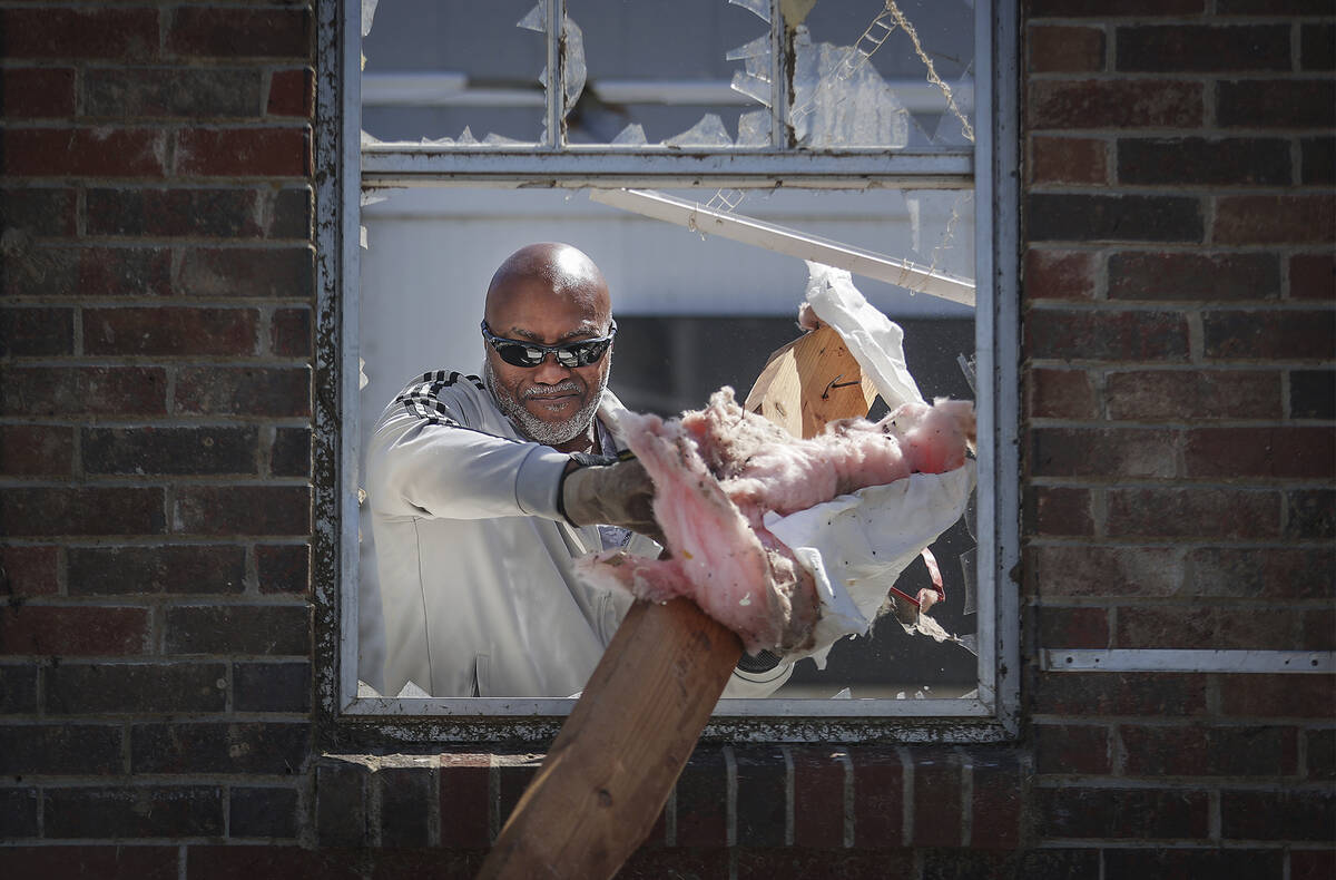 Joseph Mack helps helps neighbor Patrick Glover clean up his house in Covington, Tenn., Saturda ...