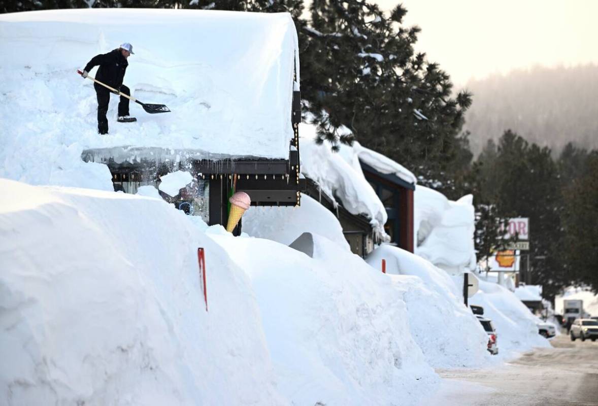 Owner Brang Miller shovels snow off the roof of Mammoth Fun Shop in Mammoth Lakes, California, ...