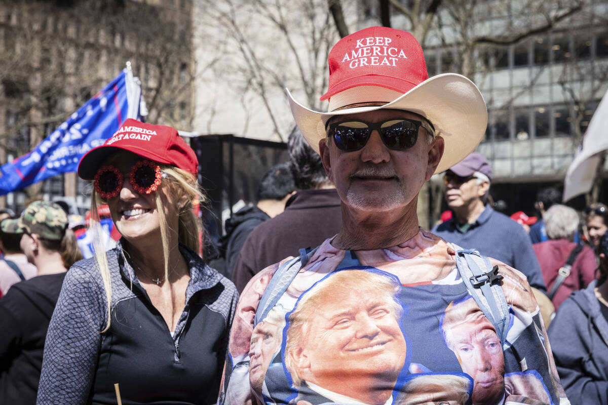 A supporter wearing a t-shirt with Former President Donald Trump's face on it attends a protest ...