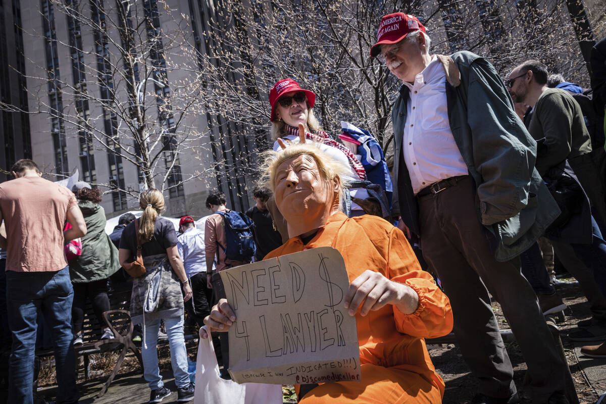 A person dressed as former President Donald Trump in an orange prison jumpsuit poses in front o ...