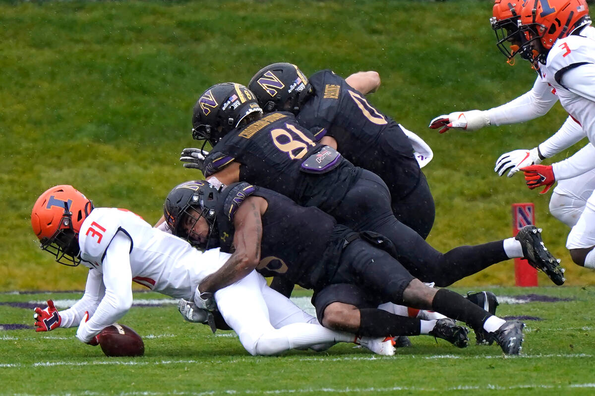 Illinois defensive back Devon Witherspoon, left, tries to recover a fumble against Northwestern ...