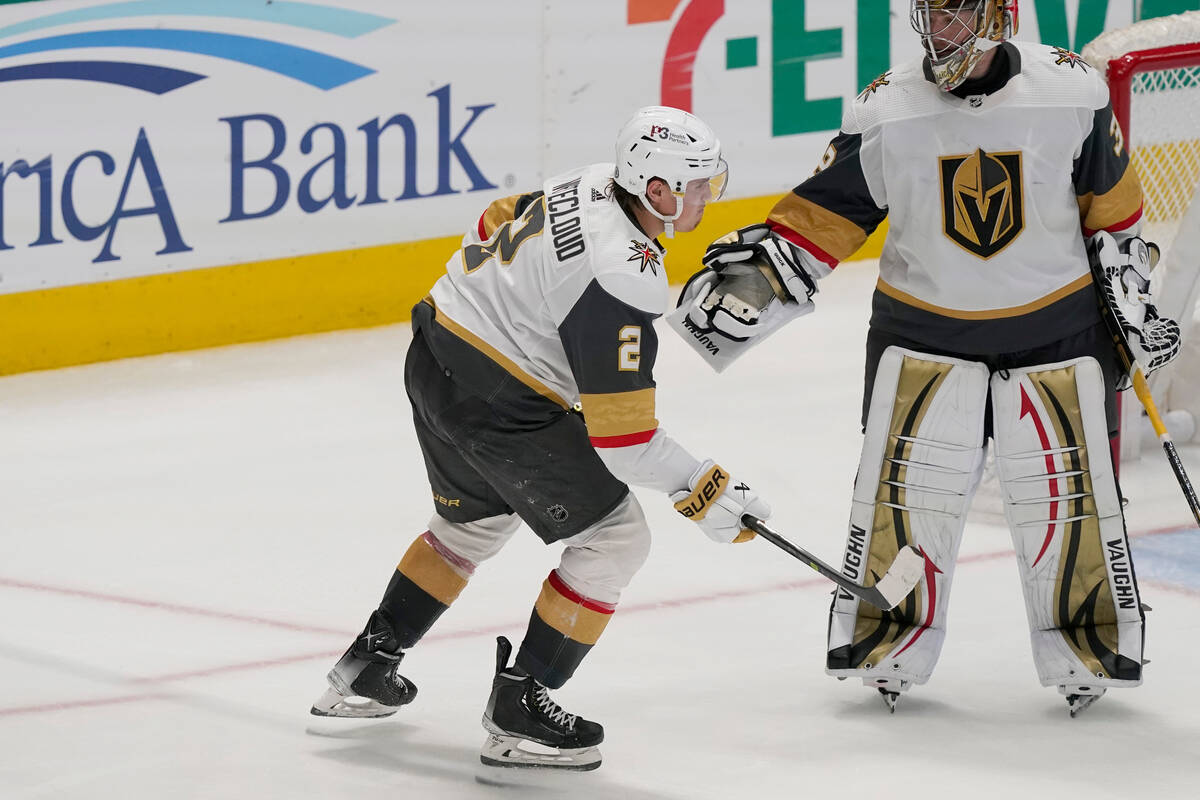 Vegas Golden Knights defenseman Zach Whitecloud (2) is checked on by teammate goaltender Jonath ...