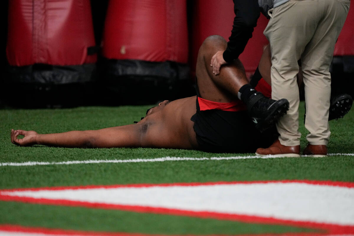 A trainer works with former Georgia defensive lineman Jalen Carter after he runs football drill ...