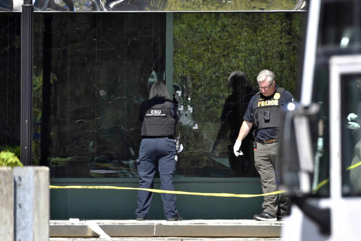 A Louisville Metro Police crime scene technician photographs bullet holes in the glass of the O ...