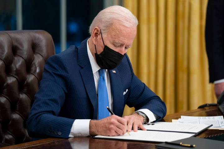 President Joe Biden signs an executive order on immigration, in the Oval Office of the White Ho ...