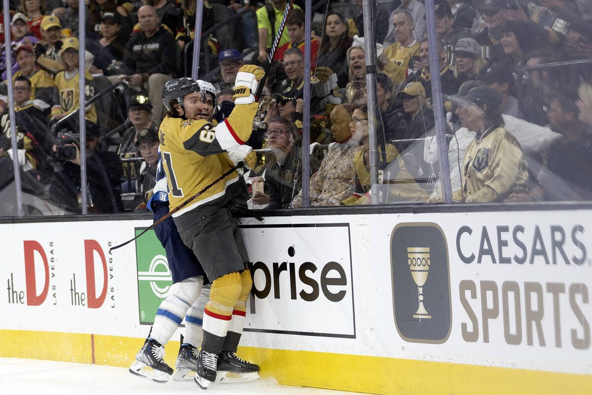 Golden Knights right wing Mark Stone (61) slams Jets center Mark Scheifele (55) into the boards ...