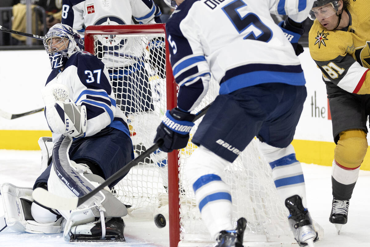 Jets goaltender Connor Hellebuyck (37) and defenseman Brenden Dillon (5) fend off a shot by Gol ...