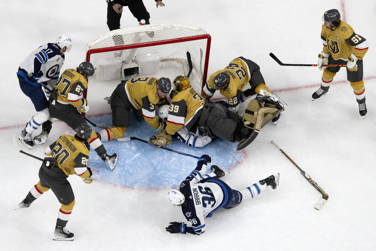 Golden Knights defenseman Brayden McNabb (3), Jets defenseman Dylan DeMelo (2) and Knights goal ...