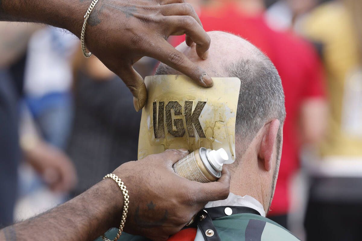 Garrett Thomas of 101 Barbershop uses golden spray to make letters, “VGK,” for hi ...