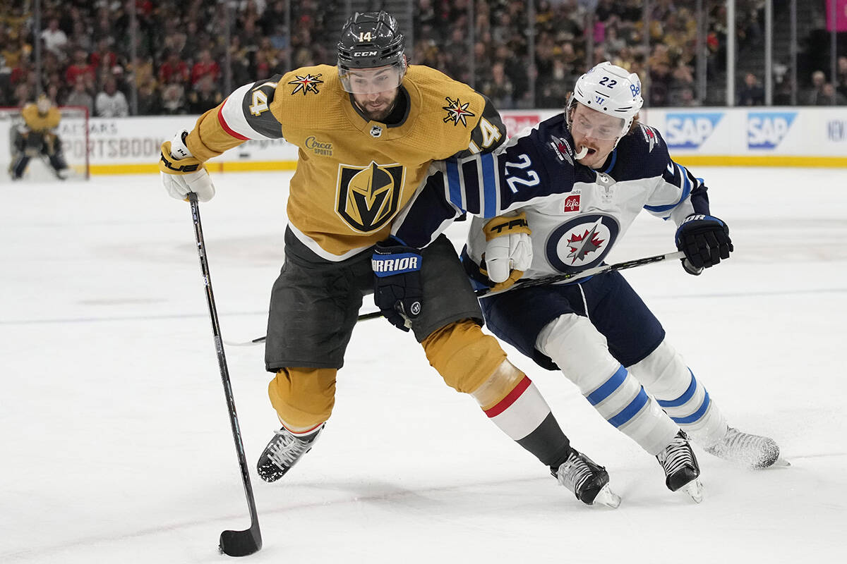 Vegas Golden Knights defenseman Nicolas Hague (14) attempts to drive aroud Winnipeg Jets center ...