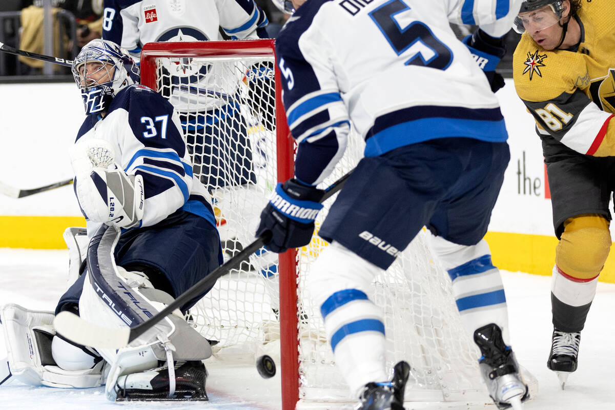 Jets goaltender Connor Hellebuyck (37) and defenseman Brenden Dillon (5) fend off a shot by Gol ...