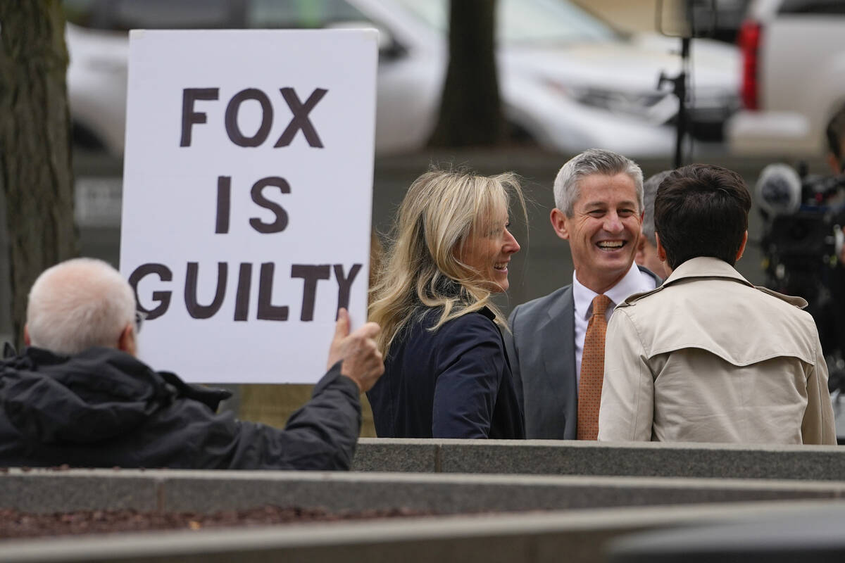 A protester holds a sign near representatives of Fox News outside the justice center for the Do ...