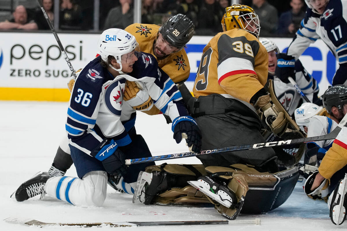 Vegas Golden Knights center Chandler Stephenson (20) helps Winnipeg Jets center Morgan Barron ( ...