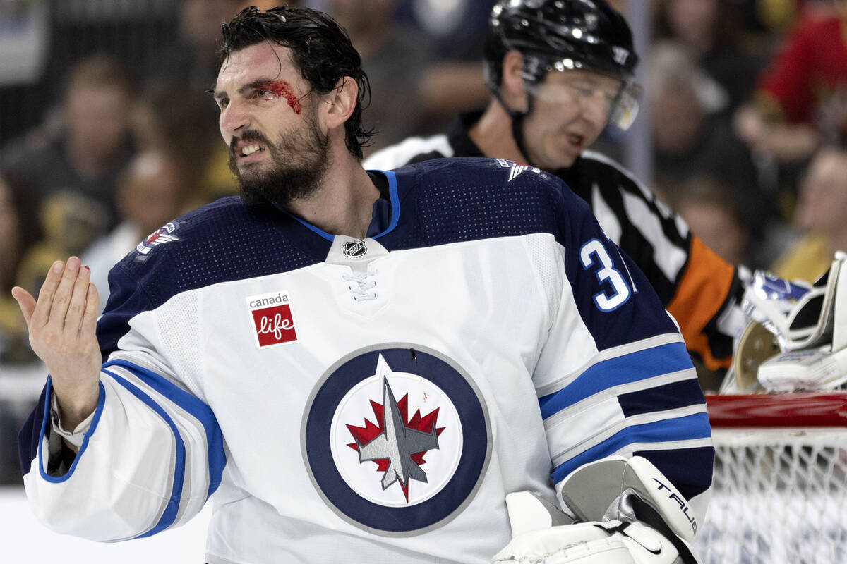 Winnipeg Jets goaltender Connor Hellebuyck (37) leaves the ice with blood on his face during th ...