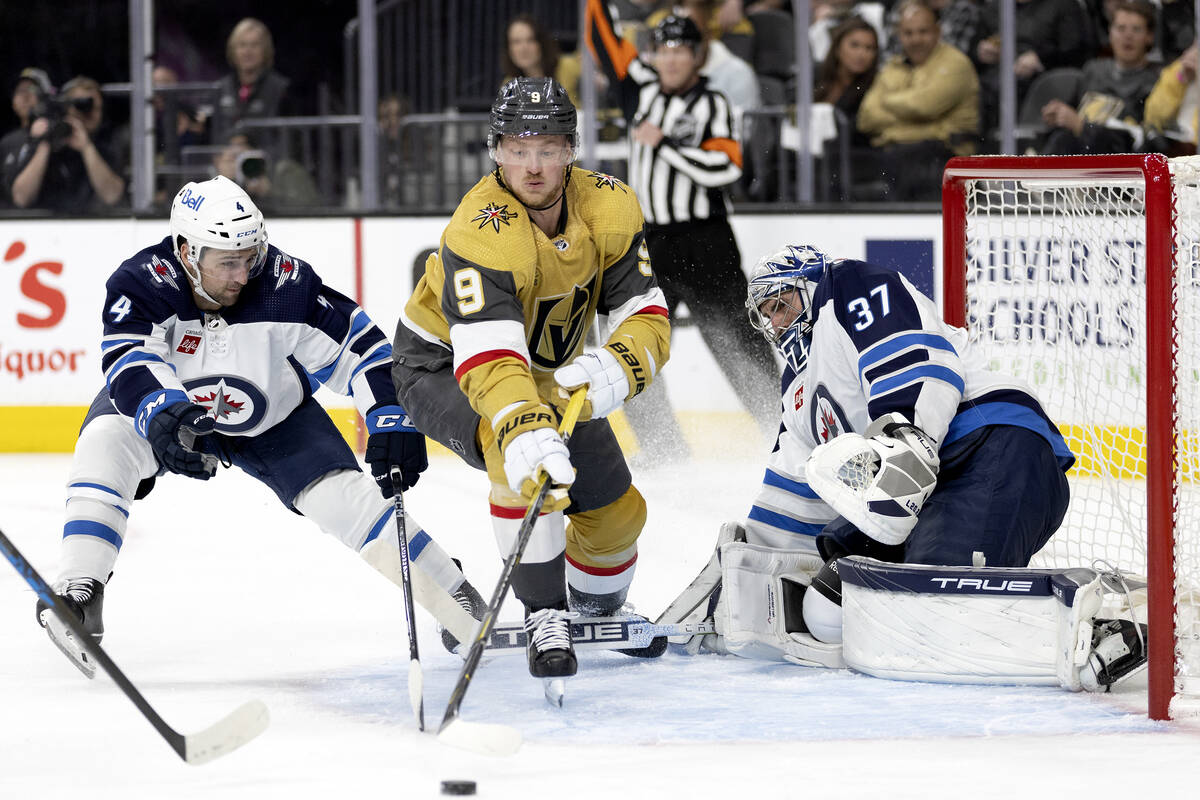 Winnipeg Jets defenseman Neal Pionk (4) edges Golden Knights center Jack Eichel (9) away from t ...