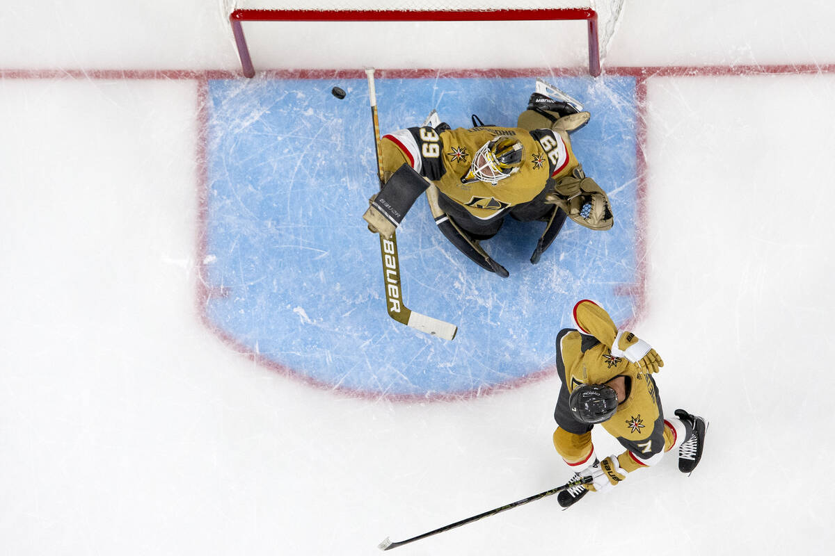 Golden Knights goaltender Laurent Brossoit (39) saves the puck while defenseman Alex Pietrangel ...