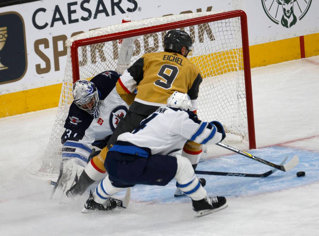 Golden Knights center Jack Eichel (9) tries to shoot against Winnipeg Jets goaltender Connor He ...