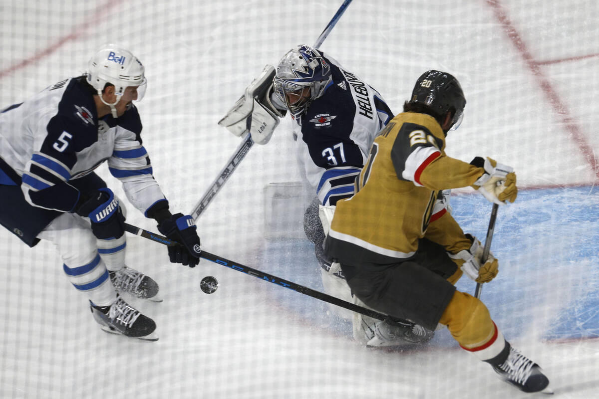 Golden Knights center Chandler Stephenson (20) tries to shoot against Winnipeg Jets goaltender ...