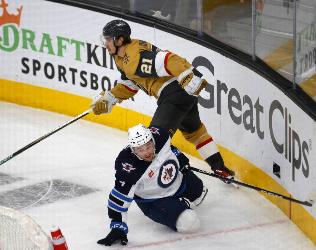 Golden Knights center Brett Howden (21) drops Winnipeg Jets defenseman Neal Pionk (4) to the ic ...