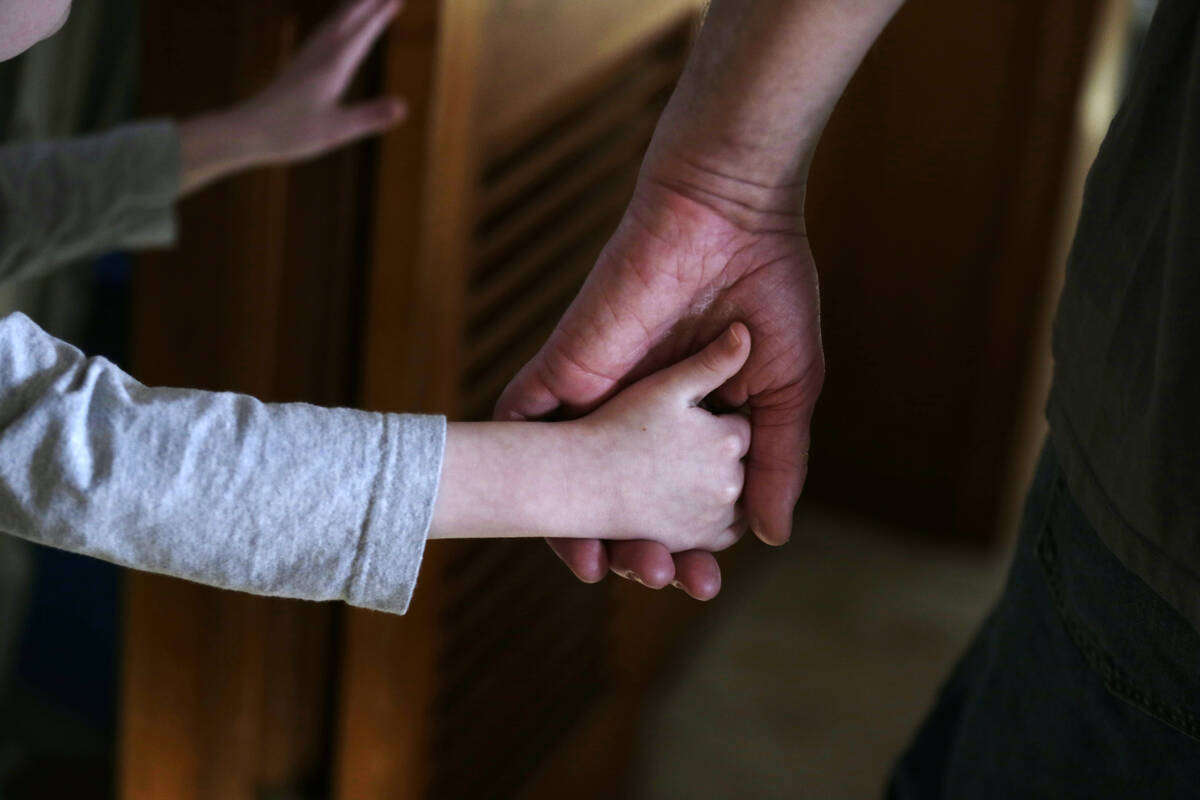 FILE - An autistic boy holds the hand of his adoptive father as they prepare to leave for a fam ...