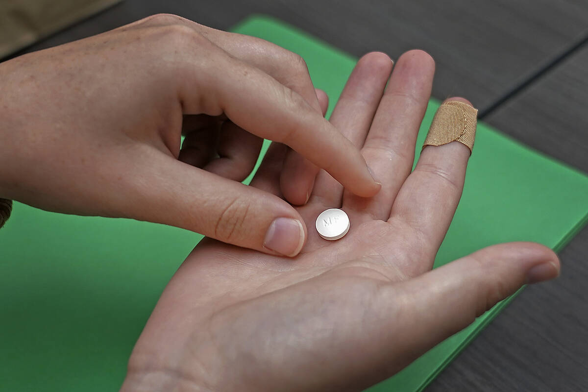 FILE - A patient prepares to take the first of two combination pills, mifepristone, for a medic ...