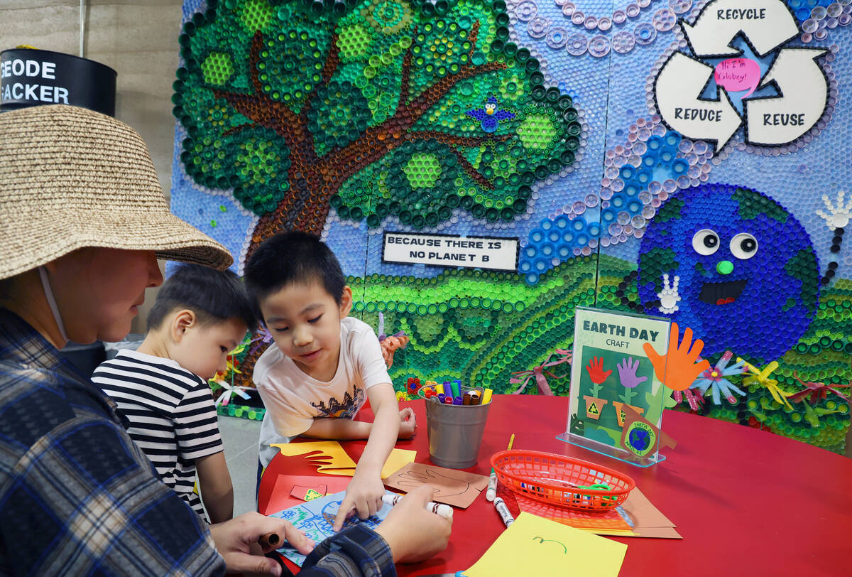 Jiyu Qiao, from left, works on a craft with sons Wesley and Jasper during an Earth Day festival ...