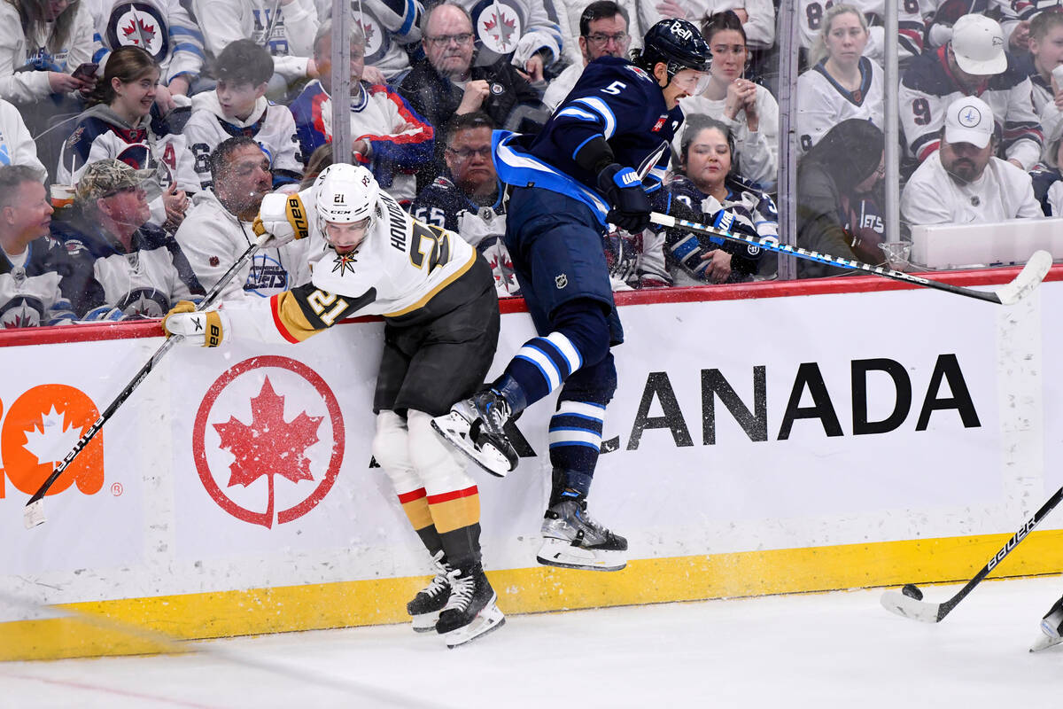 Vegas Golden Knights' Brett Howden (21) checks Winnipeg Jets' Brenden Dillon (5) during second- ...