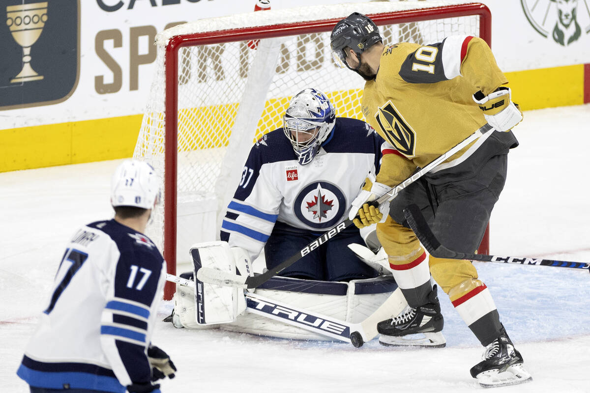 Winnipeg Jets goaltender Connor Hellebuyck (37) saves the puck while Golden Knights center Nico ...