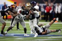 West quarterback Dorian Thompson-Robinson of UCLA (2) evades tackle by East edge rushers Yasir ...