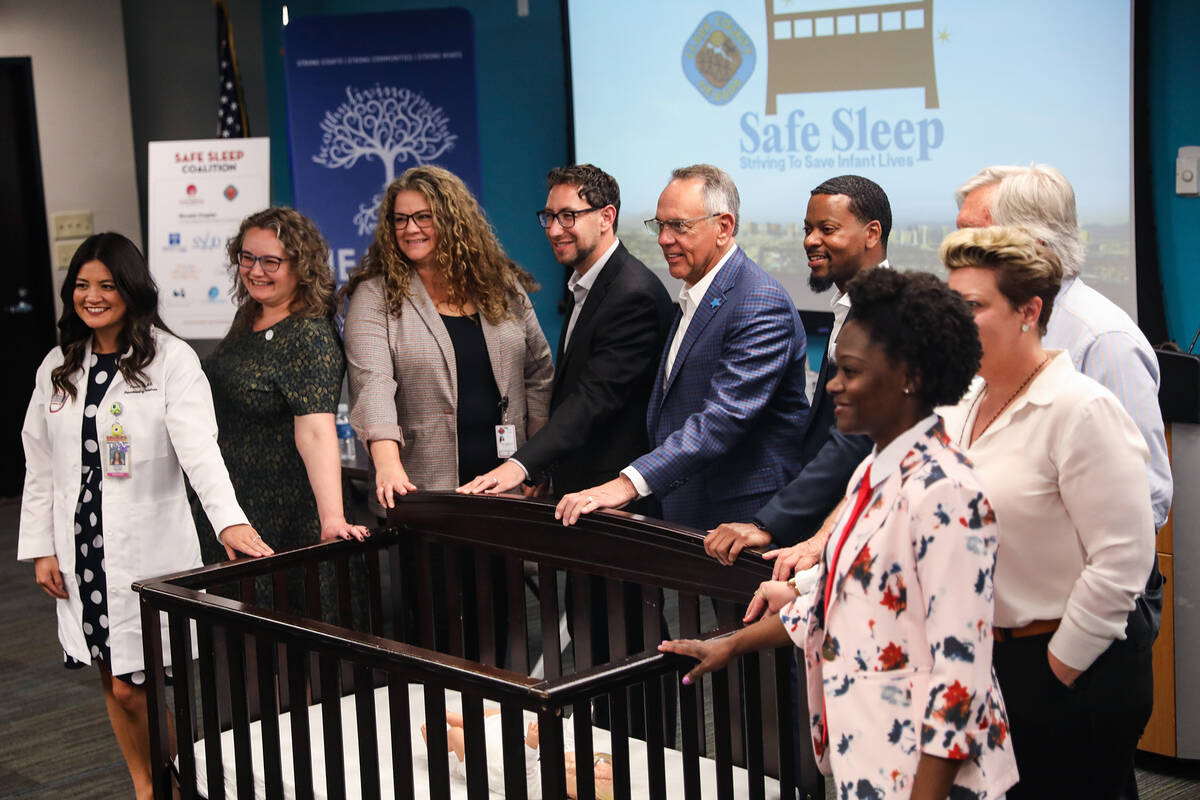 Political, health, and police officials pose for a photo surrounding a crib after a press confe ...