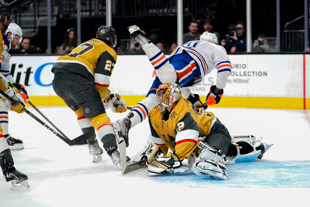 Edmonton Oilers left wing Evander Kane (91) falls over Vegas Golden Knights goaltender Jonathan ...