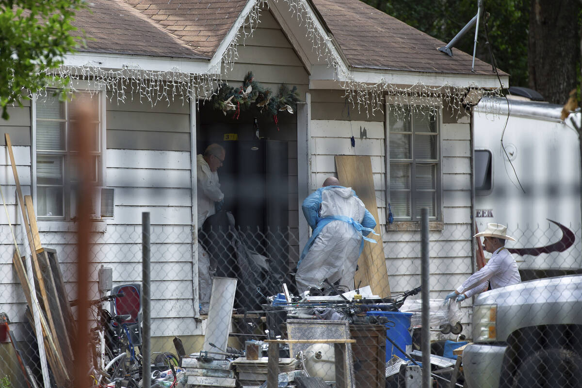 Law enforcement authorities removing bodies from a scene where five people were shot the night ...