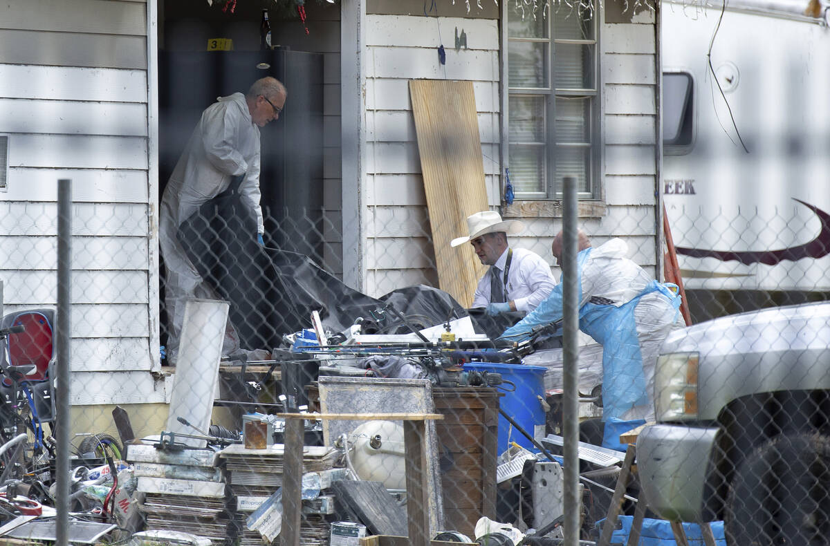 Law enforcement authorities removing bodies from a scene where five people were shot the night ...