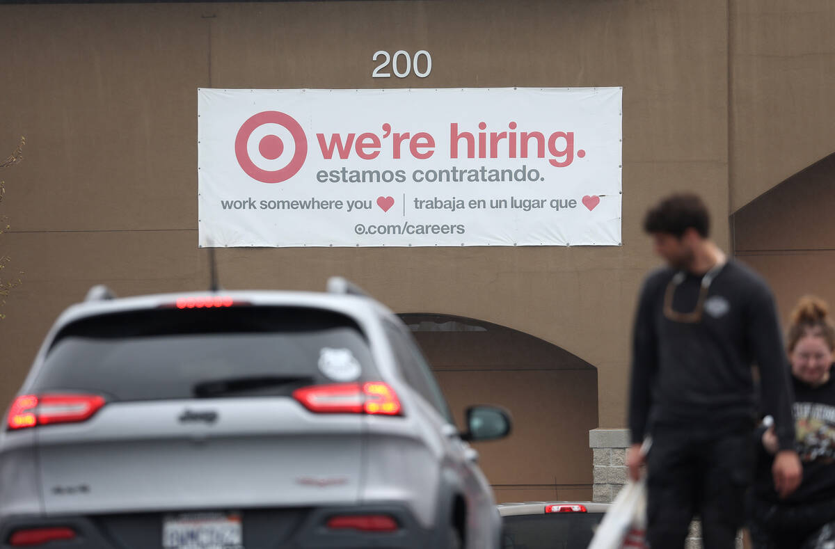 People walk by a hiring sign posted on the exterior of a Target store on April 7, 2023, in Nova ...