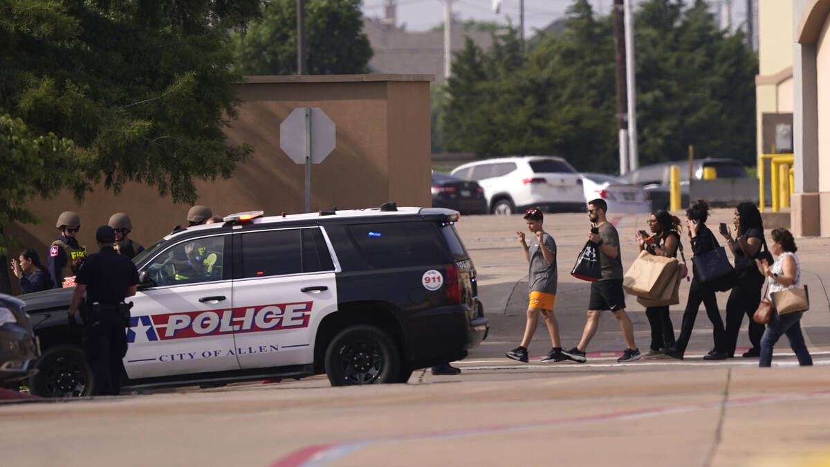 People raise their hands as they leave a shopping center following reports of a shooting, Satur ...